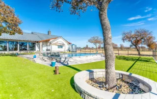 Residential backyard with custom pool, green turf, and established tree landscaping