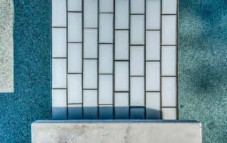 Detailed view of white vertical subway tile finish on a custom pool wall by Redfin Pools