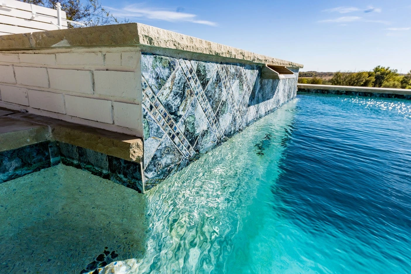 LOFTIN2-1 Custom infinity edge pool with decorative green marble tile spillway and stone retaining wall